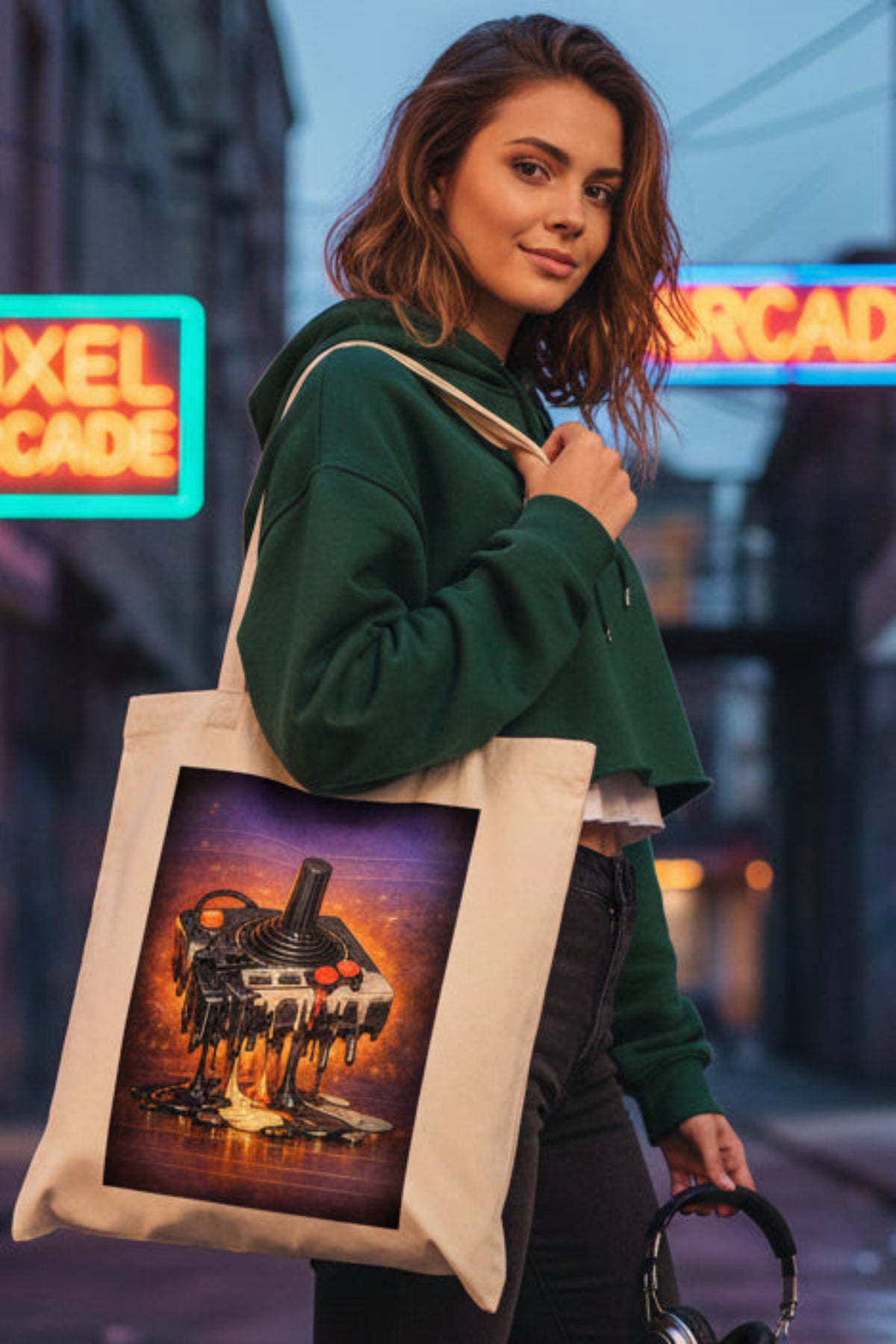 A cream-colored canvas tote bag featuring a large rectangular graphic print of a melting retro video game joystick console on a purple and orange background.