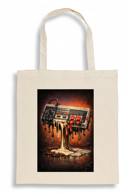 A cream-colored canvas tote bag featuring a rectangular graphic print of a melting retro video game controller dripping dark wax-like material onto a warm, fiery background.