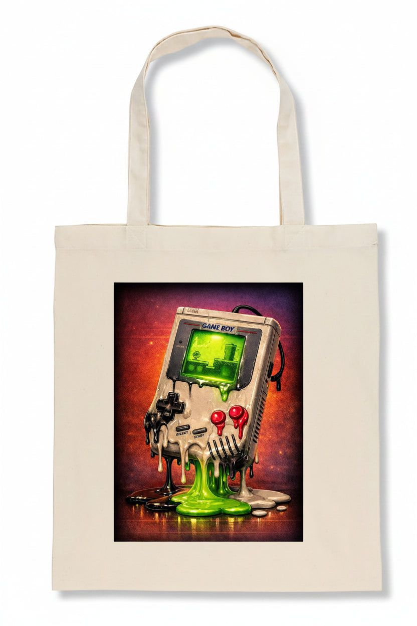 A cream-colored canvas tote bag featuring a square graphic print of a retro Game Boy covered in dripping green slime against a dark red and purple background.