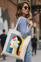 A cream-colored canvas tote bag featuring a Bauhaus-style geometric art print of a woman's profile with red, yellow, black, and blue shapes. The text 'BAUHAUS' is printed in white near the bottom of the graphic.