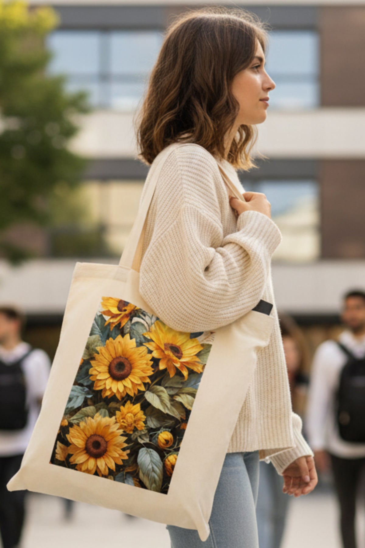 A natural canvas tote bag featuring a large rectangular graphic print of vibrant yellow sunflowers with green leaves on the front, set against a plain white background.