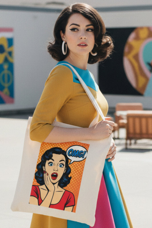 A cream-colored canvas tote bag featuring a retro pop-art graphic of a surprised woman with a speech bubble that says 'OMG!' on a solid white background.