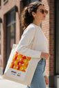 A cream-colored canvas tote bag featuring a retro graphic print with overlapping orange, yellow, and red circles, and text reading 'brauhaus', 'mottellus', '20 09 1923'.