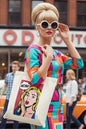 A cream-colored canvas tote bag featuring a pop-art graphic of a surprised blonde woman with a 'WOW!' speech bubble on a red polka-dot background.