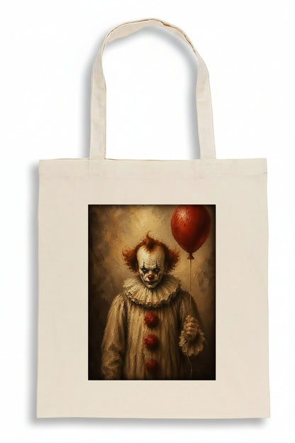 An off-white canvas tote bag featuring a printed graphic of a creepy clown holding a red balloon, set against a plain white background.