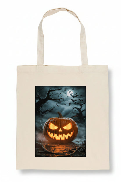 A cream-colored canvas tote bag featuring a rectangular graphic print of a glowing jack-o'-lantern pumpkin in a spooky, dark forest scene with bats and bare trees.