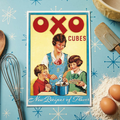 Vintage OXO Cubes box front artwork with large red OXO lettering, a yellow background, a blue border, and an illustration of a woman and two children mixing ice cream in a pot. The text 'New Recipes of Flavor' appears at the bottom.